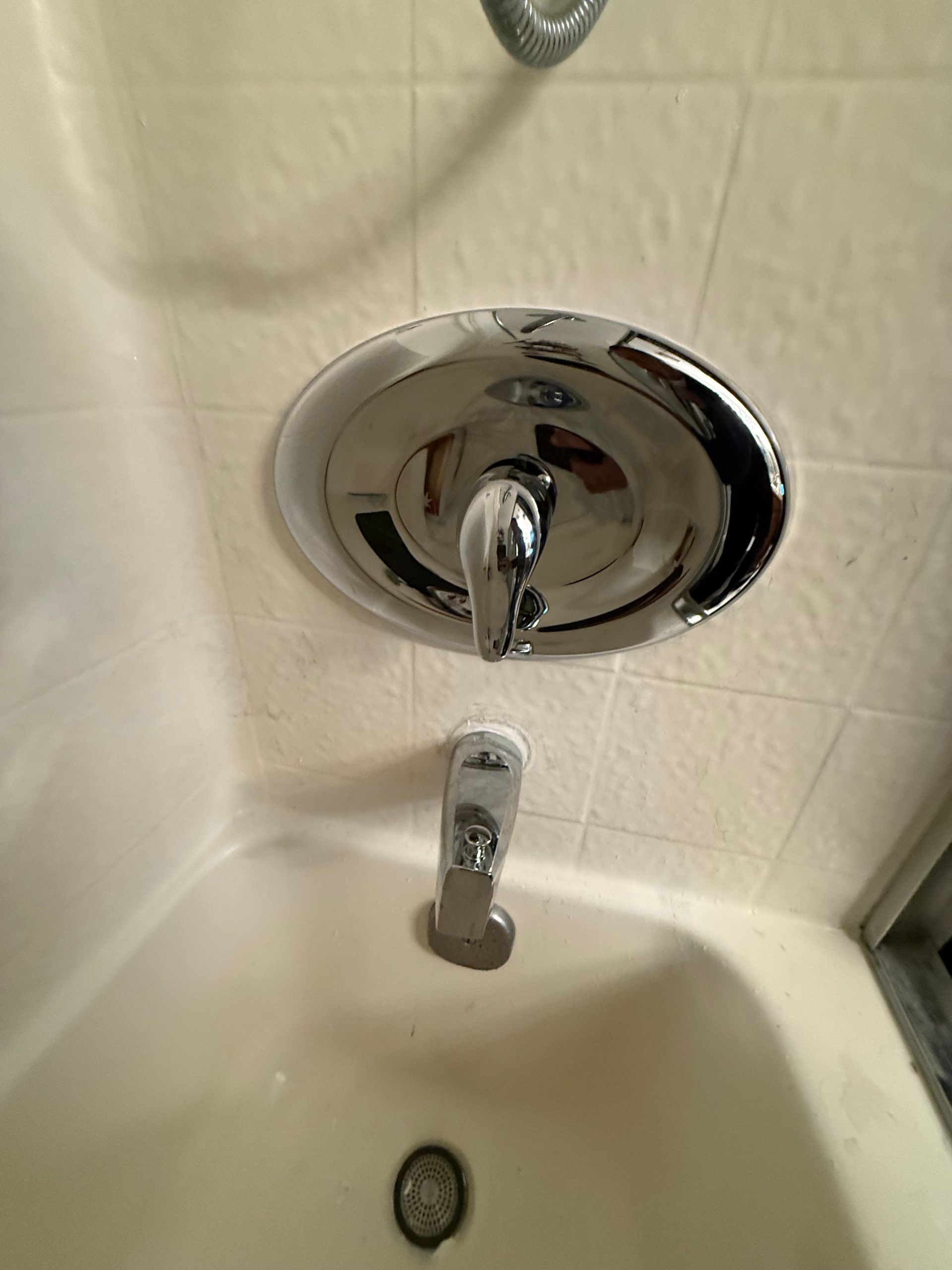 A bathtub with a chrome shower head and faucet