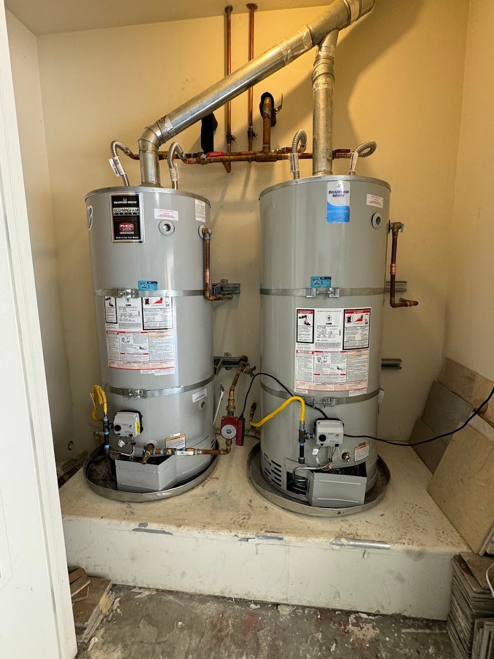 Two water heaters are sitting next to each other in a room.