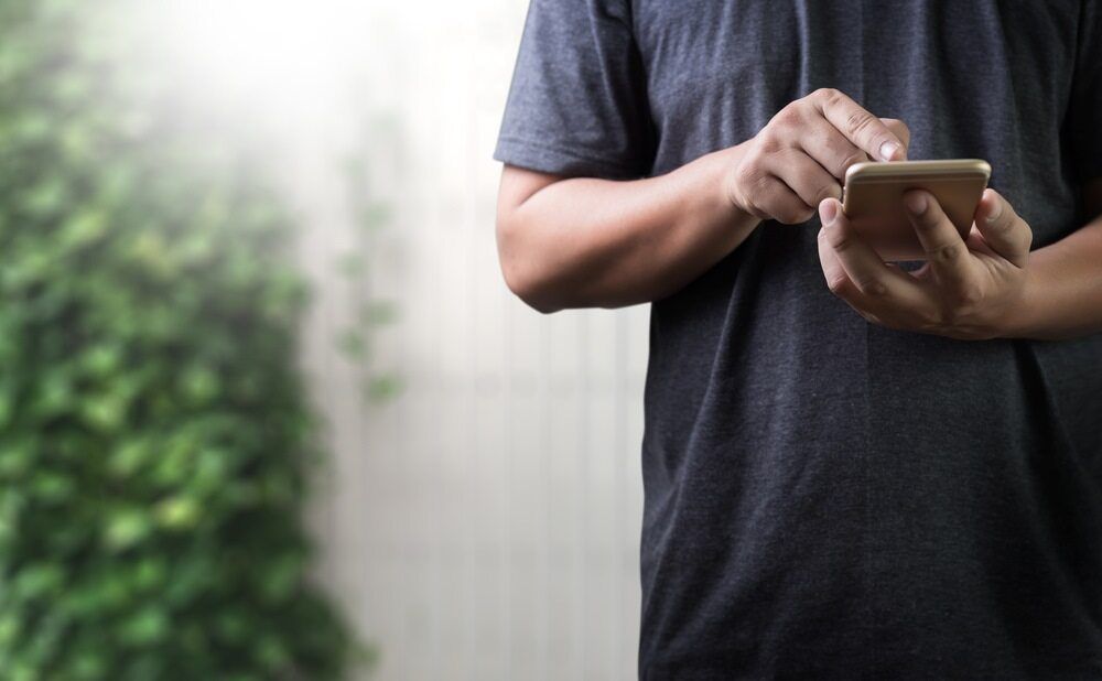 A Man Is Holding A Cell Phone In His Hands — Equiptranz In Kybong, QLD