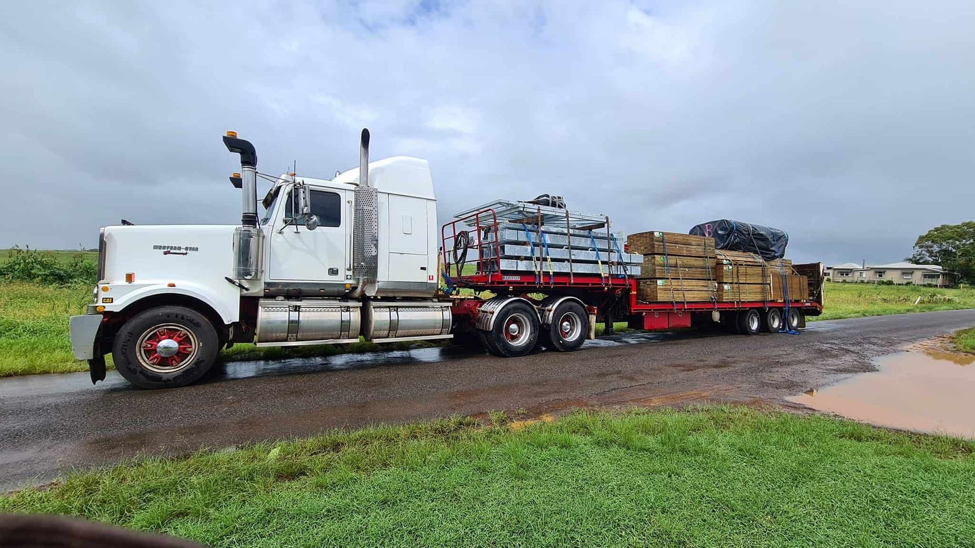 A white semi truck is driving down a wet road. — Equiptranz In Kybong, QLD