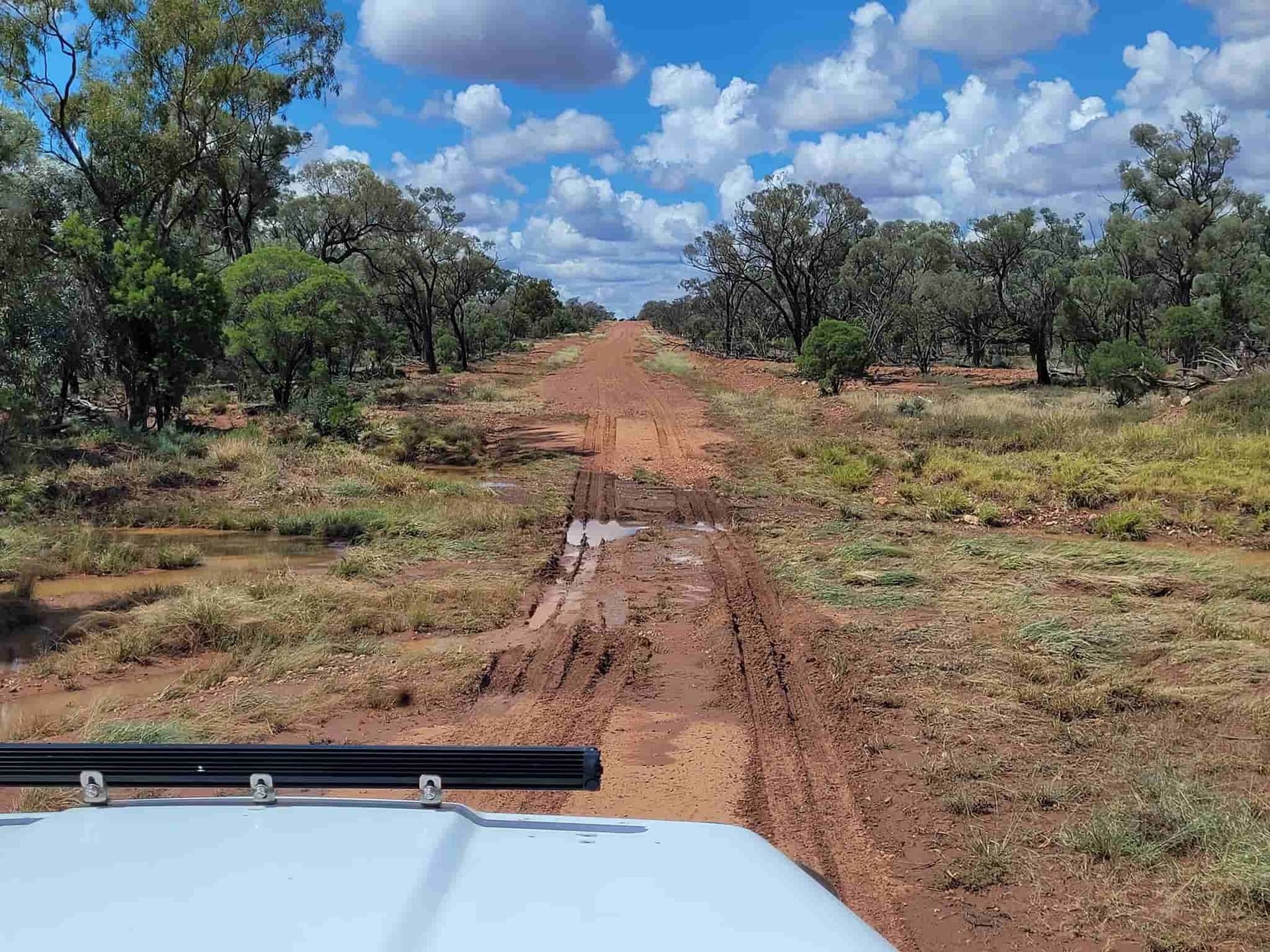 A Muddy Dirt Road In The Middle Of A Field With Trees On The Side — Equiptranz In Kybong, QLD