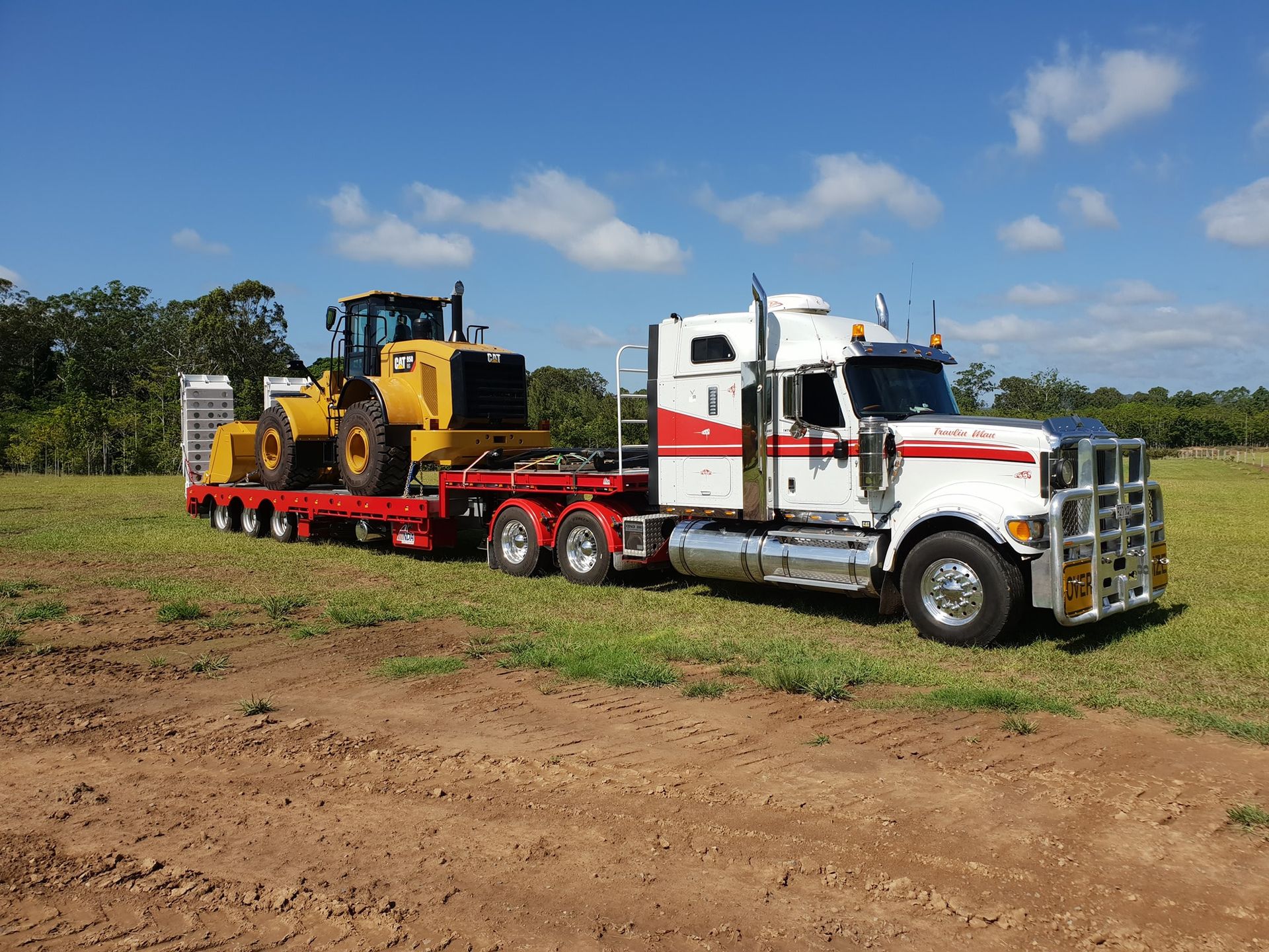 A semi truck is carrying a bulldozer on a flatbed trailer. — Equiptranz In Kybong, QLD