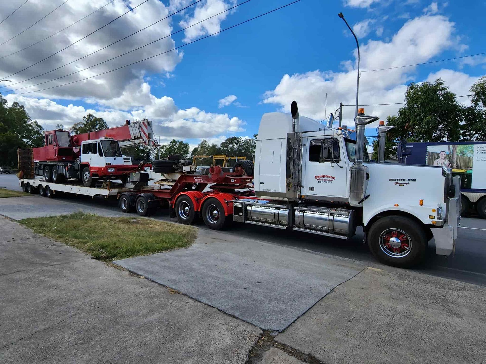 A White Semi Truck Is Carrying A Crane On A Flatbed Trailer — Equiptranz In Kybong, QLD