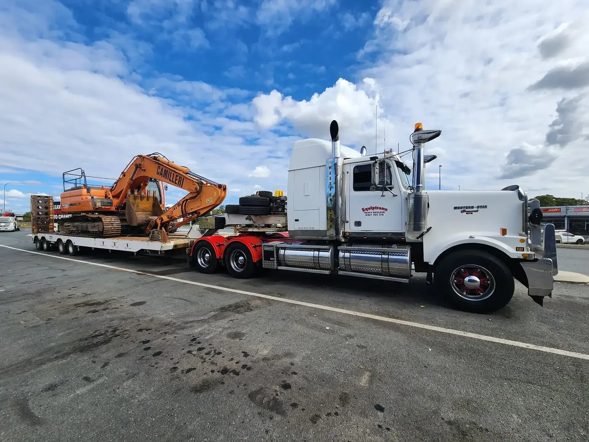 A semi truck is carrying a large excavator on a trailer. — Equiptranz In Kybong, QLD