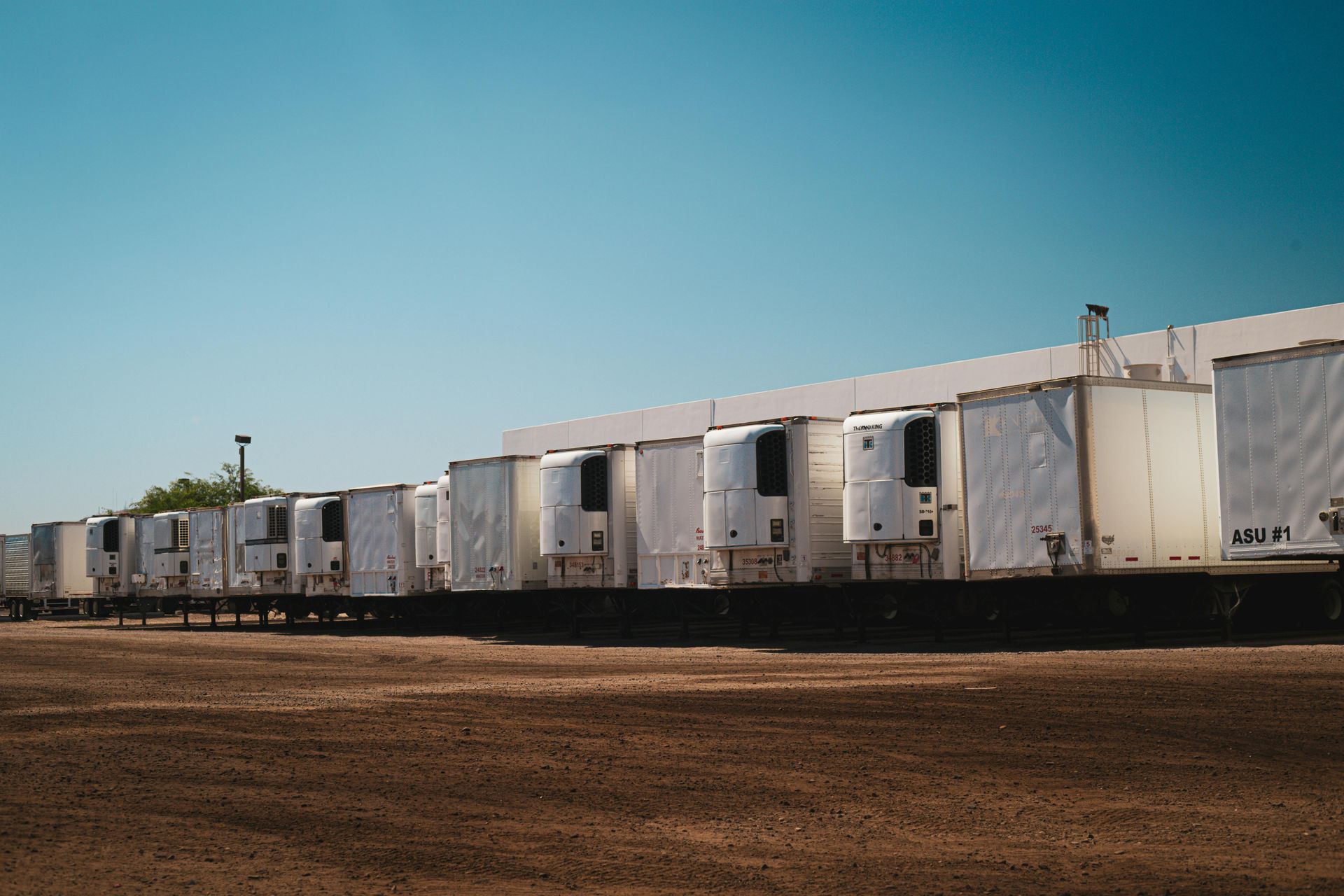 A row of white trailers are parked in front of a building. — Equiptranz In Kybong, QLD