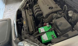 Car engine bay with a green battery.