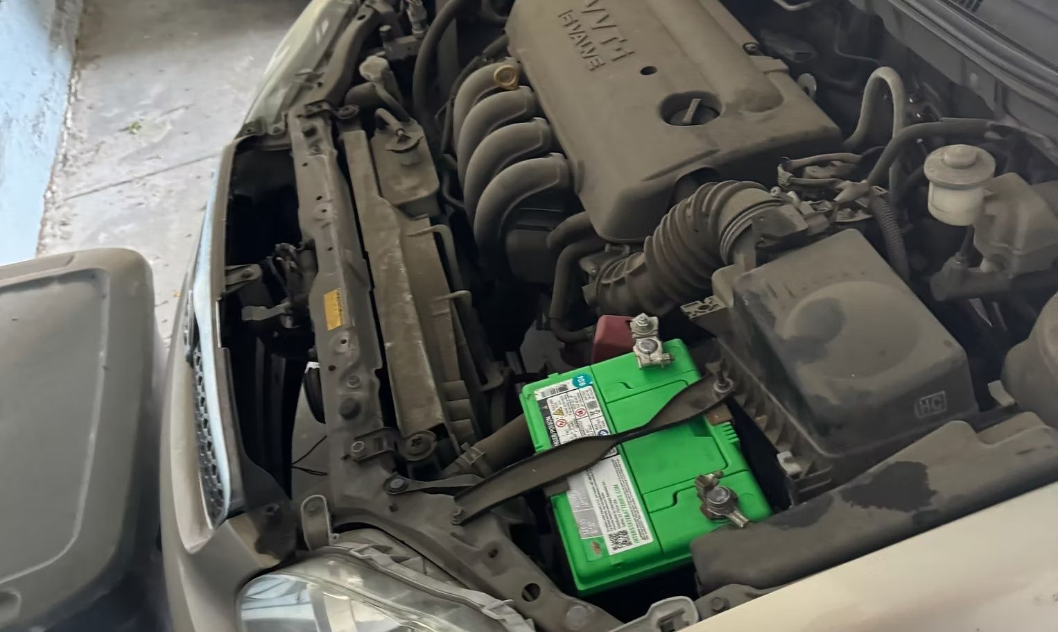 Car engine bay with a green battery.