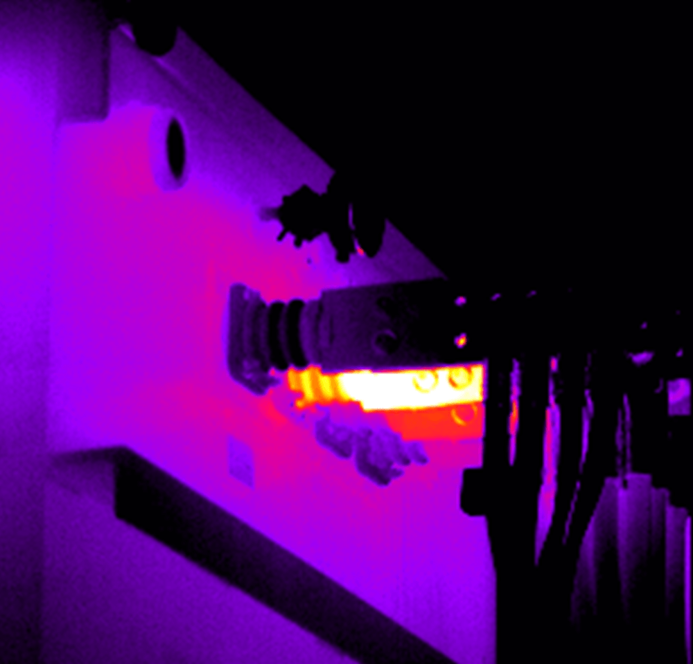 A purple light is shining on a wall in a dark room.