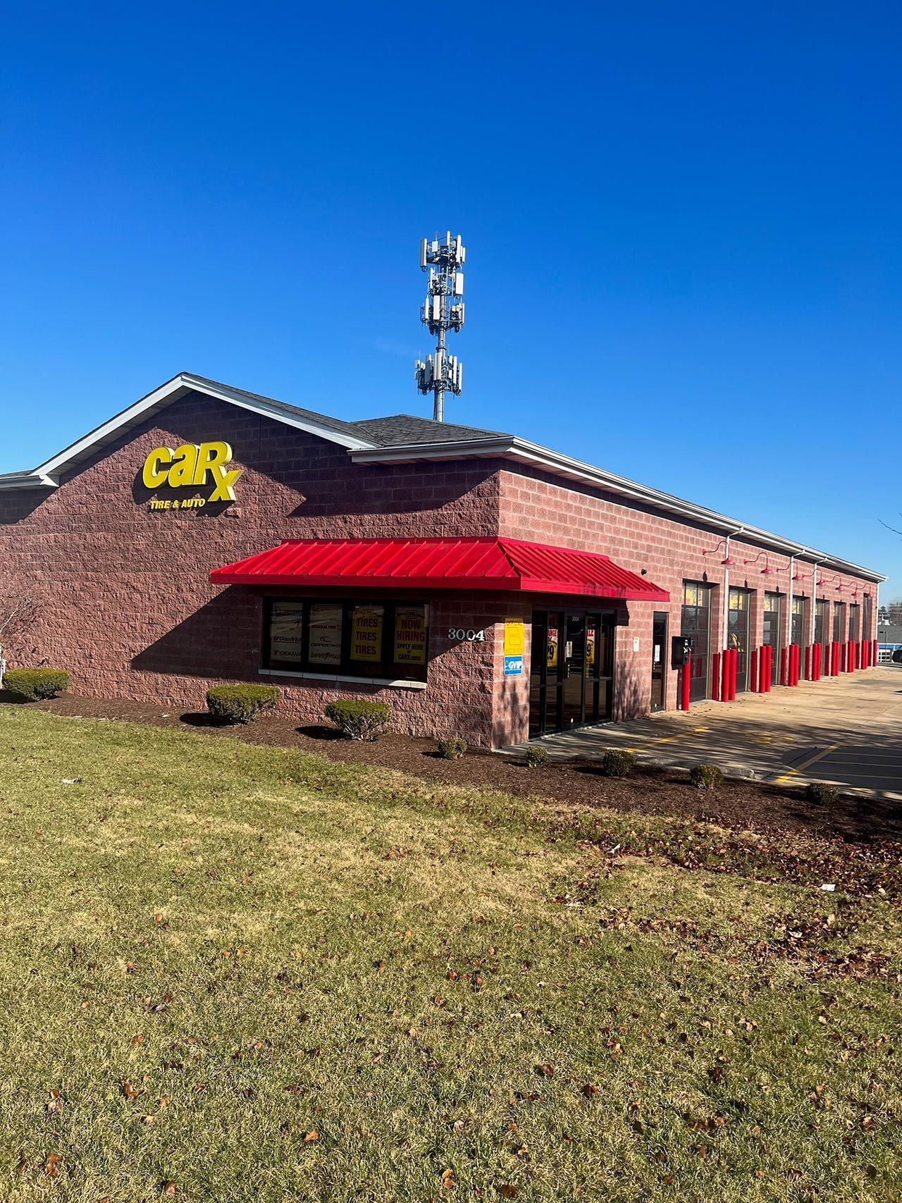 Brick building with red awning, CAR sign, and antenna tower against a blue sky.
