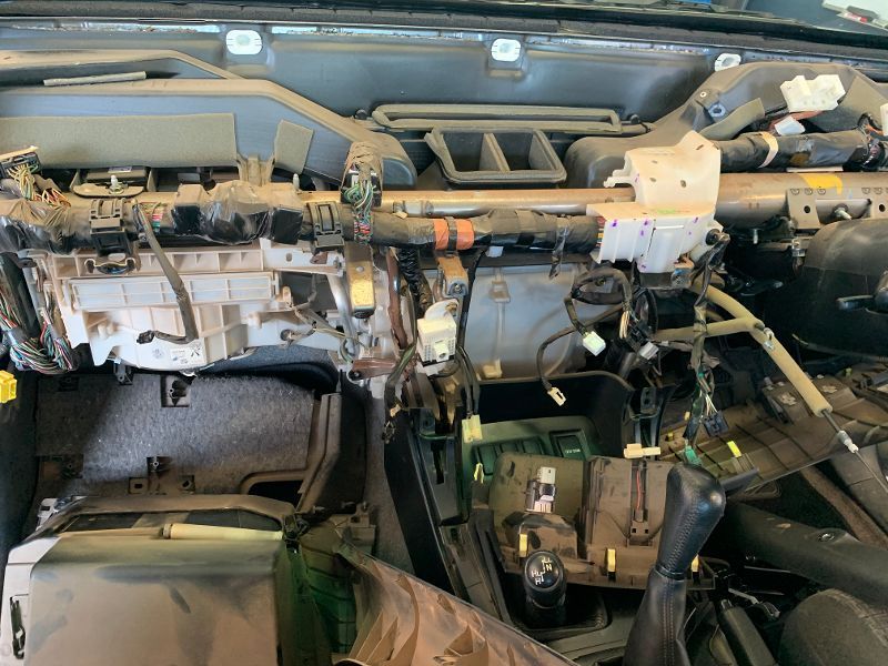Mechanic in Blue Jumpsuit Checks a Car Battery With a Digital Tester — Pelican Motors Service Centre in Caloundra West, QLD