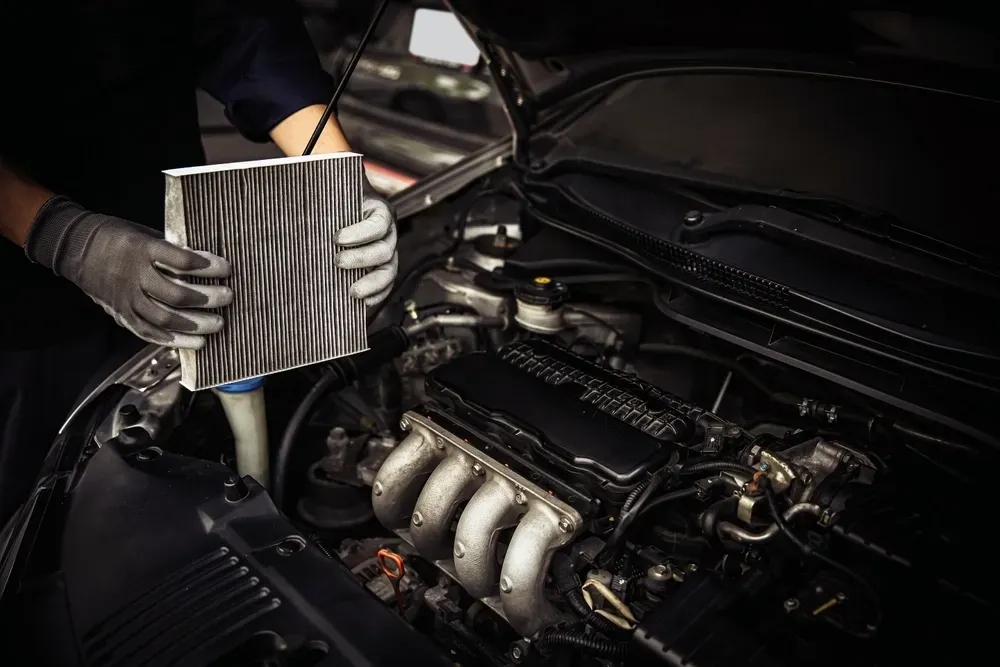 Mechanic replacing an air filter in a car engine compartment. — Pelican Motors Service Centre in Caloundra West, QLD