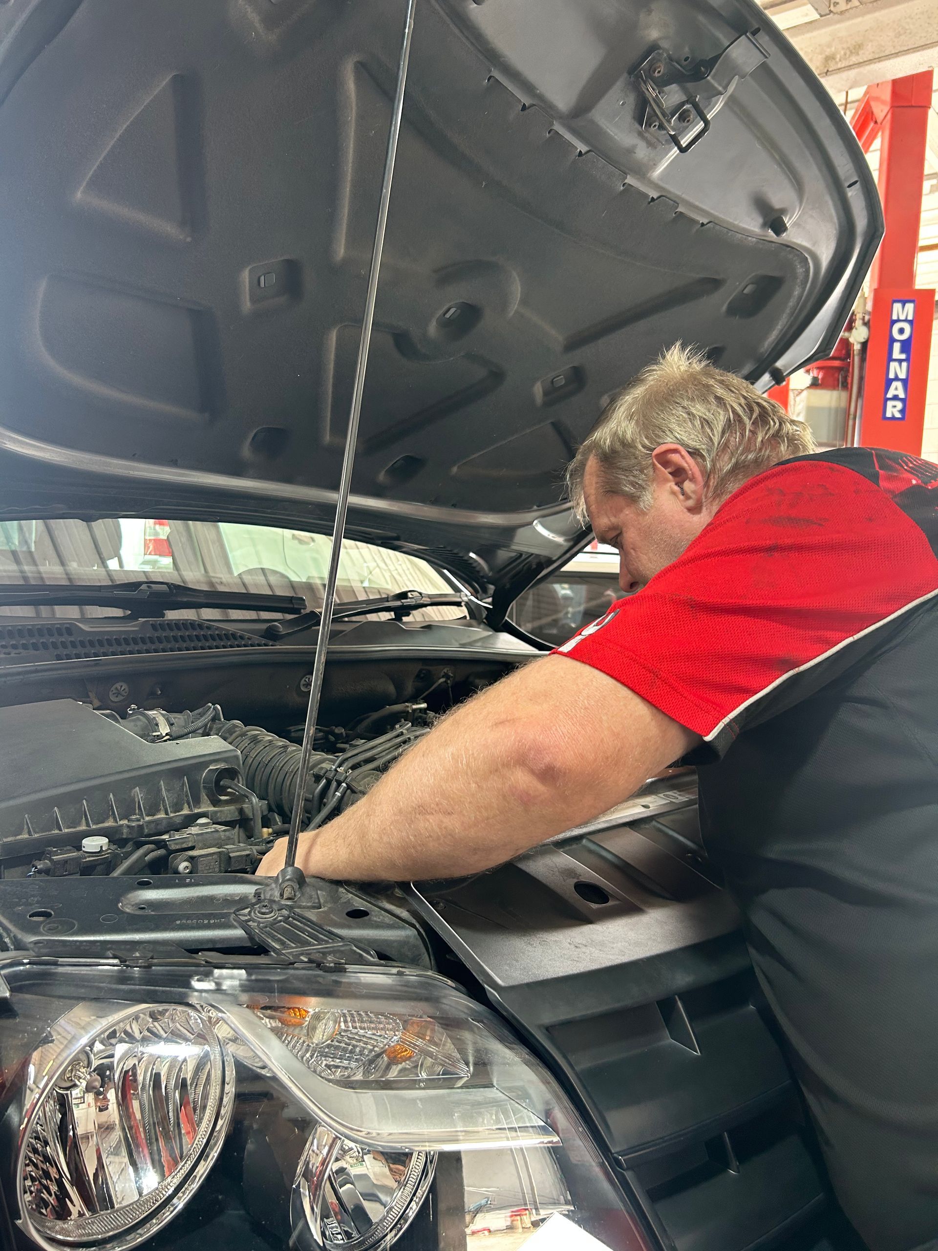 A Car is Sitting on a Lift in a Garage — Pelican Motors Service Centre In Caloundra West, QLD
