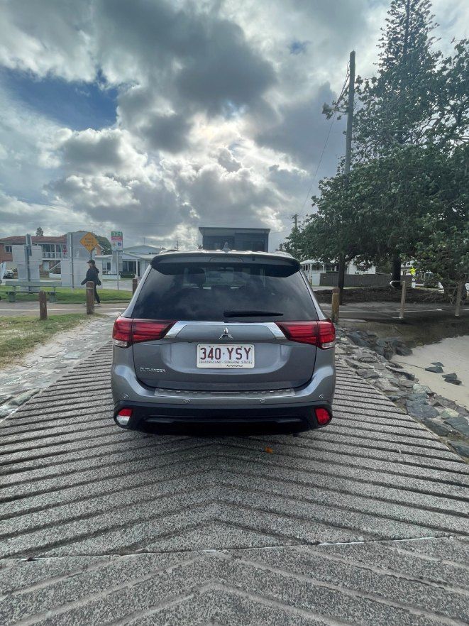 A Gray Mitsubishi Outlander is Parked on the Side of a Road — Pelican Motors Service Centre In Caloundra West, QLD 