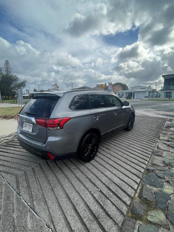A Gray Car is Parked on a Cobblestone Driveway on a Cloudy — Pelican Motors Service Centre In Caloundra West, QLD day.