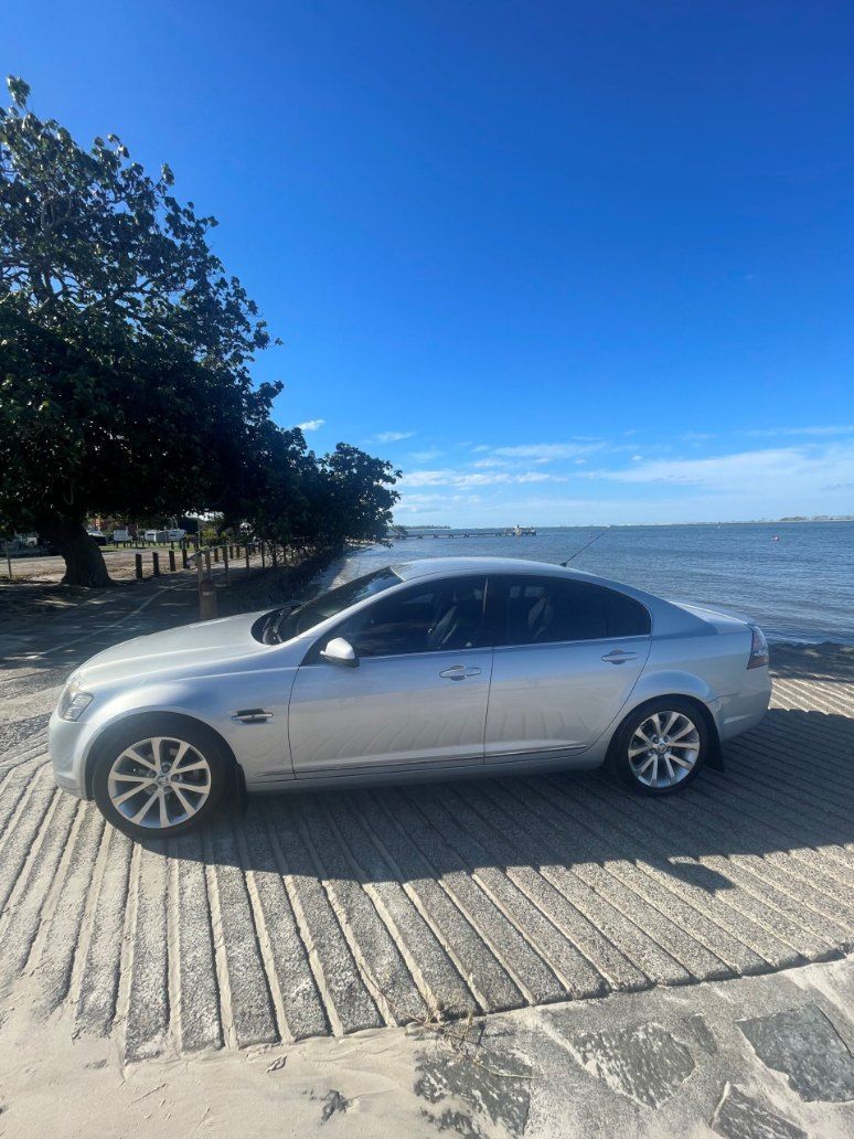 A Silver Car is Parked on a Beach Next to the Ocean — Pelican Motors Service Centre In Caloundra West, QLD 
