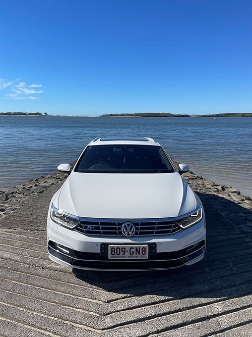A White Car is Parked on a Dock Next to a Body of Water — Pelican Motors Service Centre In Caloundra West, QLD 