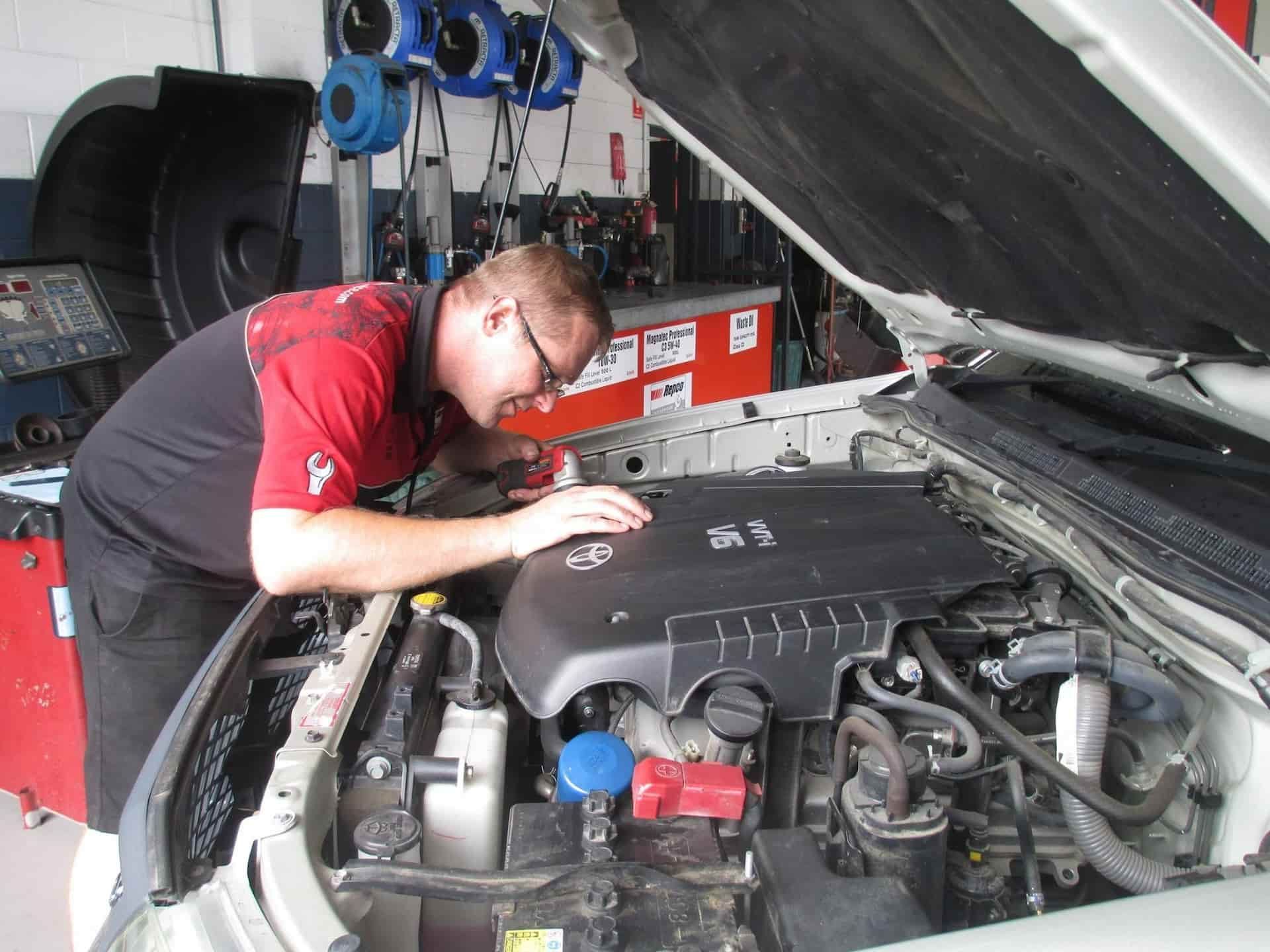 A Man is Working Under the Hood of a Car — Pelican Motors Service Centre In Caloundra West, QLD