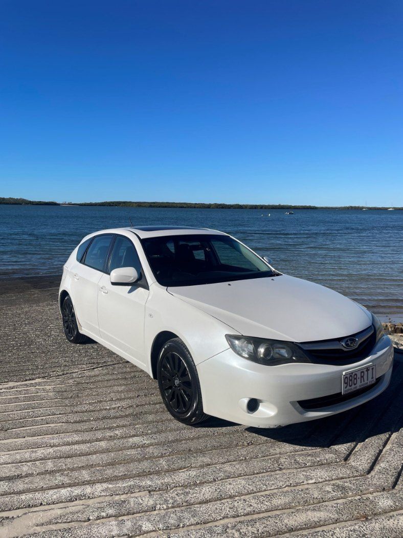 A White Car is Parked on a Dock Next to a Body of Water — Pelican Motors Service Centre In Caloundra West, QLD 