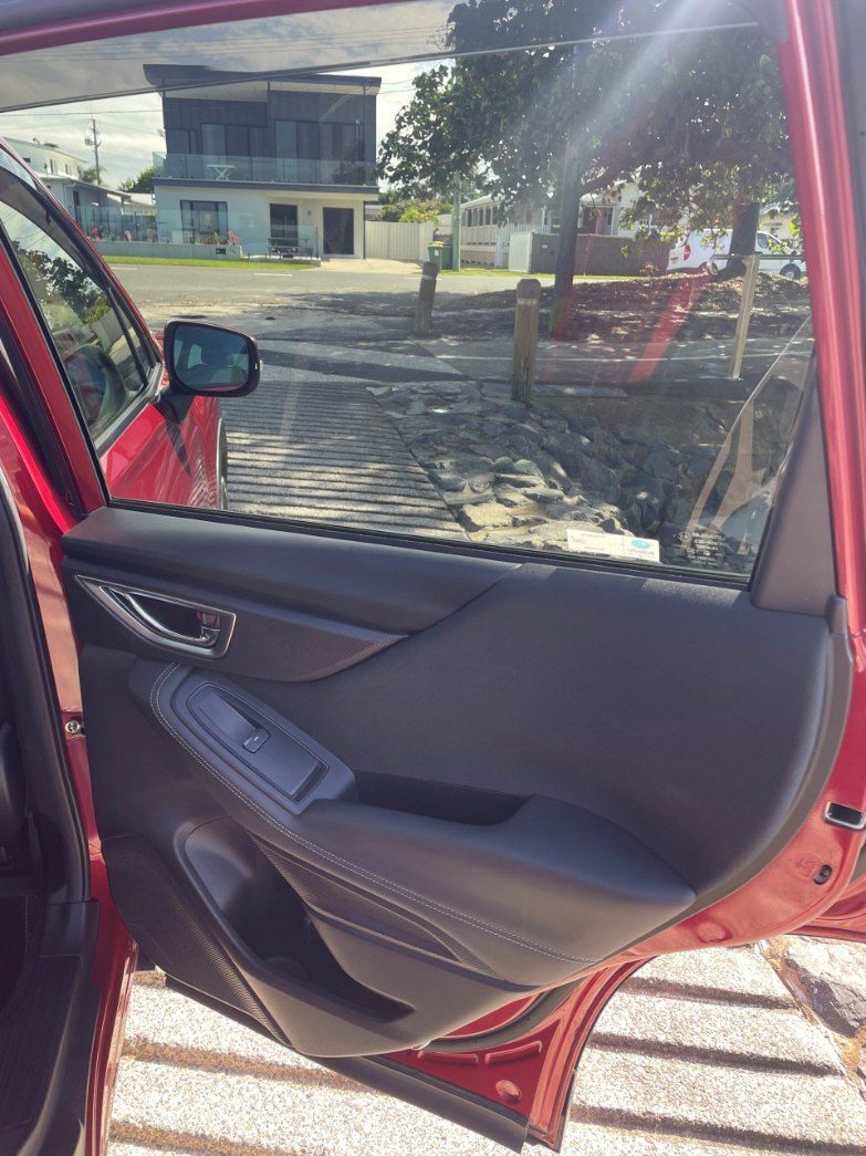 A Red Car With the Door Open is Parked in Front of a House — Pelican Motors Service Centre In Caloundra West, QLD 