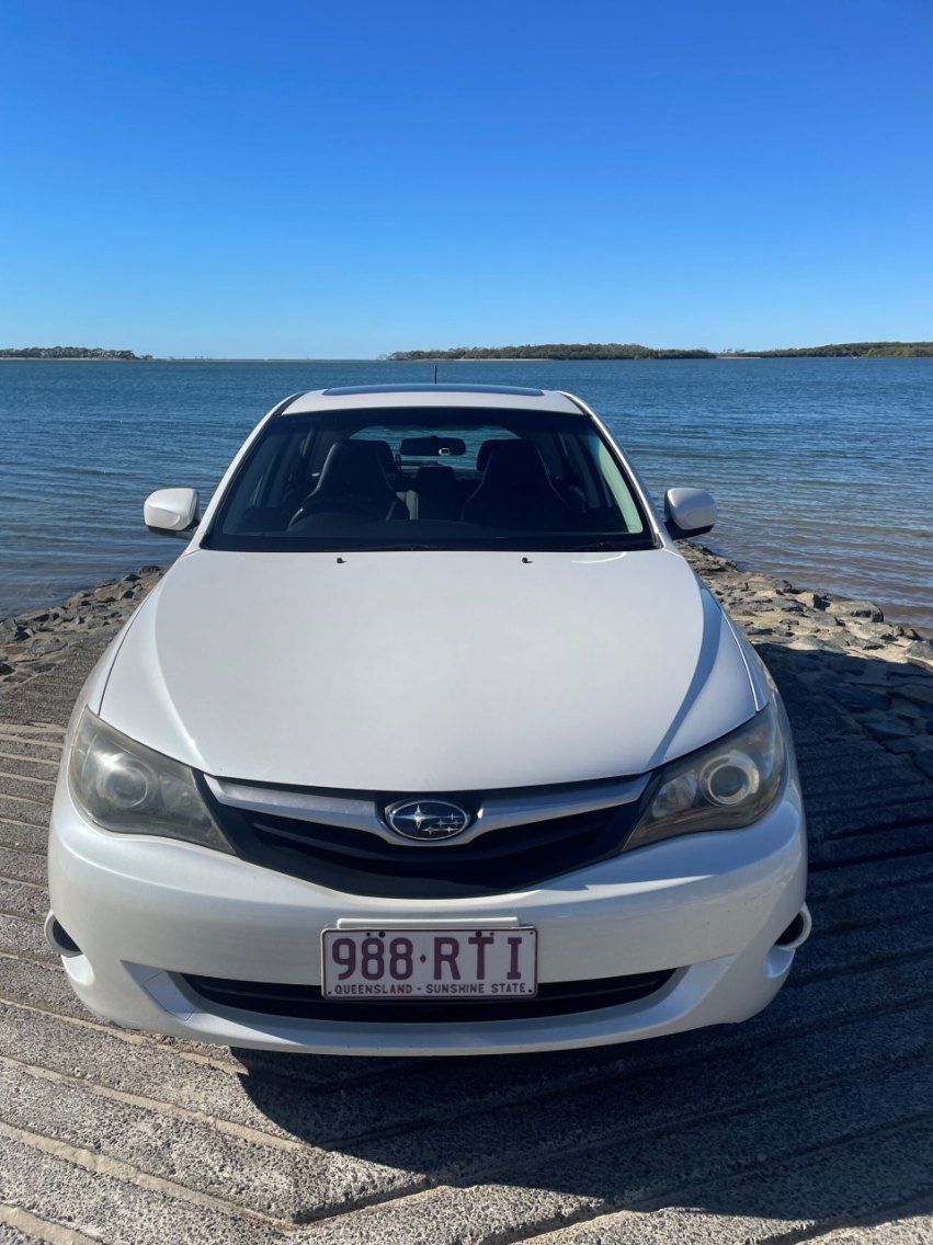 A White Subaru Car is Parked on the Beach Near the Water — Pelican Motors Service Centre In Caloundra West, QLD 