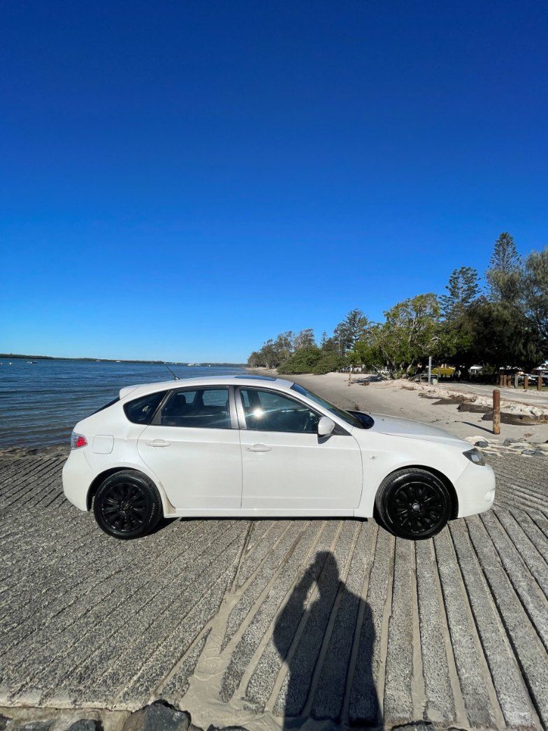 A White Car is Parked on a Wooden Pier Next to a Body of Water — Pelican Motors Service Centre In Caloundra West, QLD 