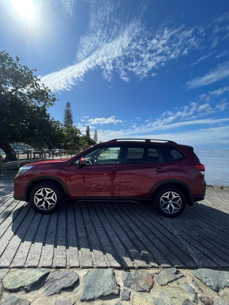 A Red Suv is Parked on a Wooden Pier Next to a Body of Water — Pelican Motors Service Centre In Caloundra West, QLD 