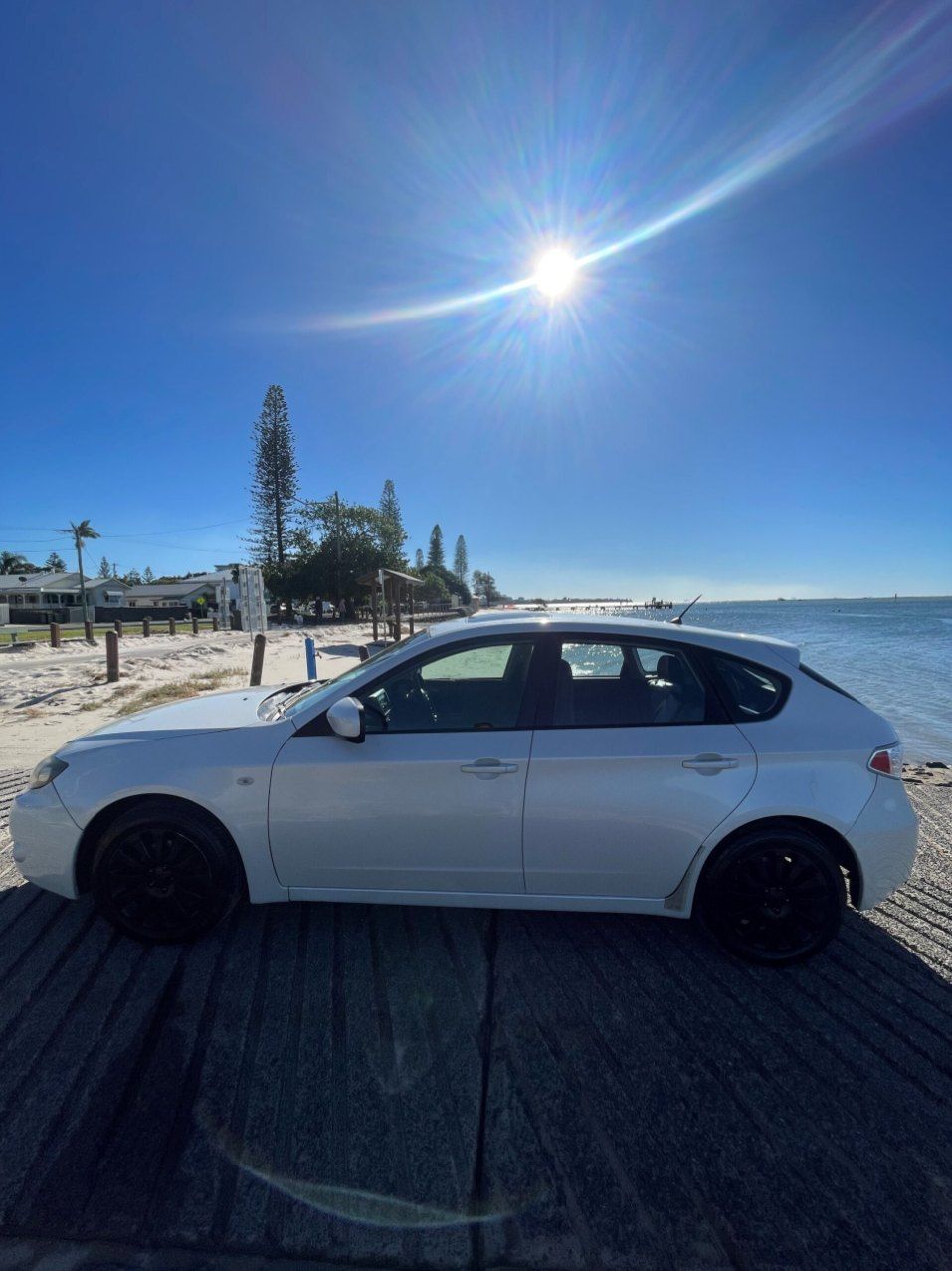 A White Car is Parked on the Beach Next to the Water — Pelican Motors Service Centre In Caloundra West, QLD 