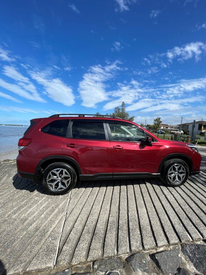 A Red Subaru Forester is Parked on a Wooden Deck Next to the Ocean — Pelican Motors Service Centre In Caloundra West, QLD 