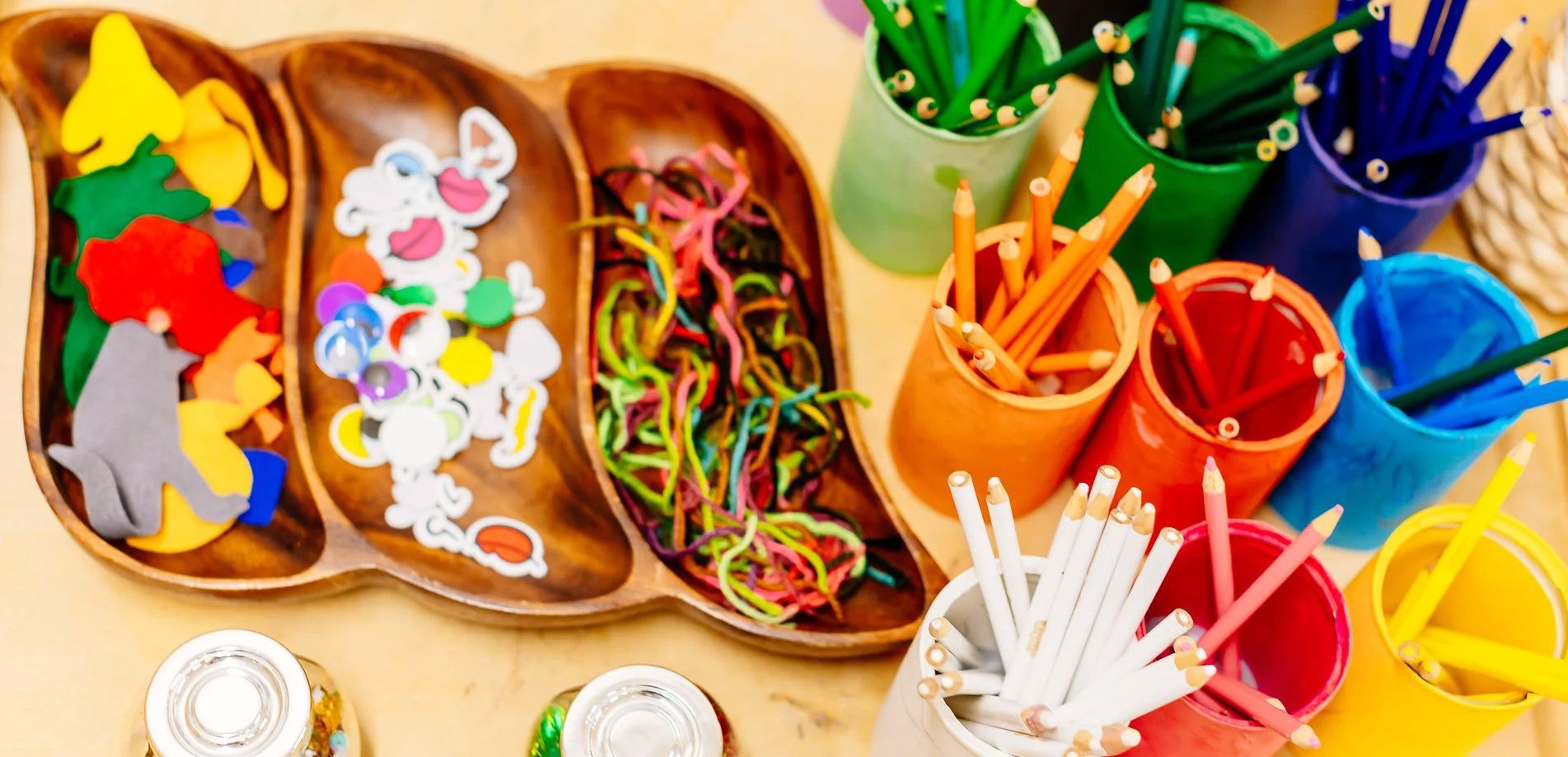 a wooden tray filled with toys and pencils on a table .