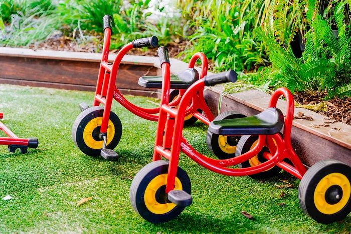 two red tricycles are parked next to each other on the grass .