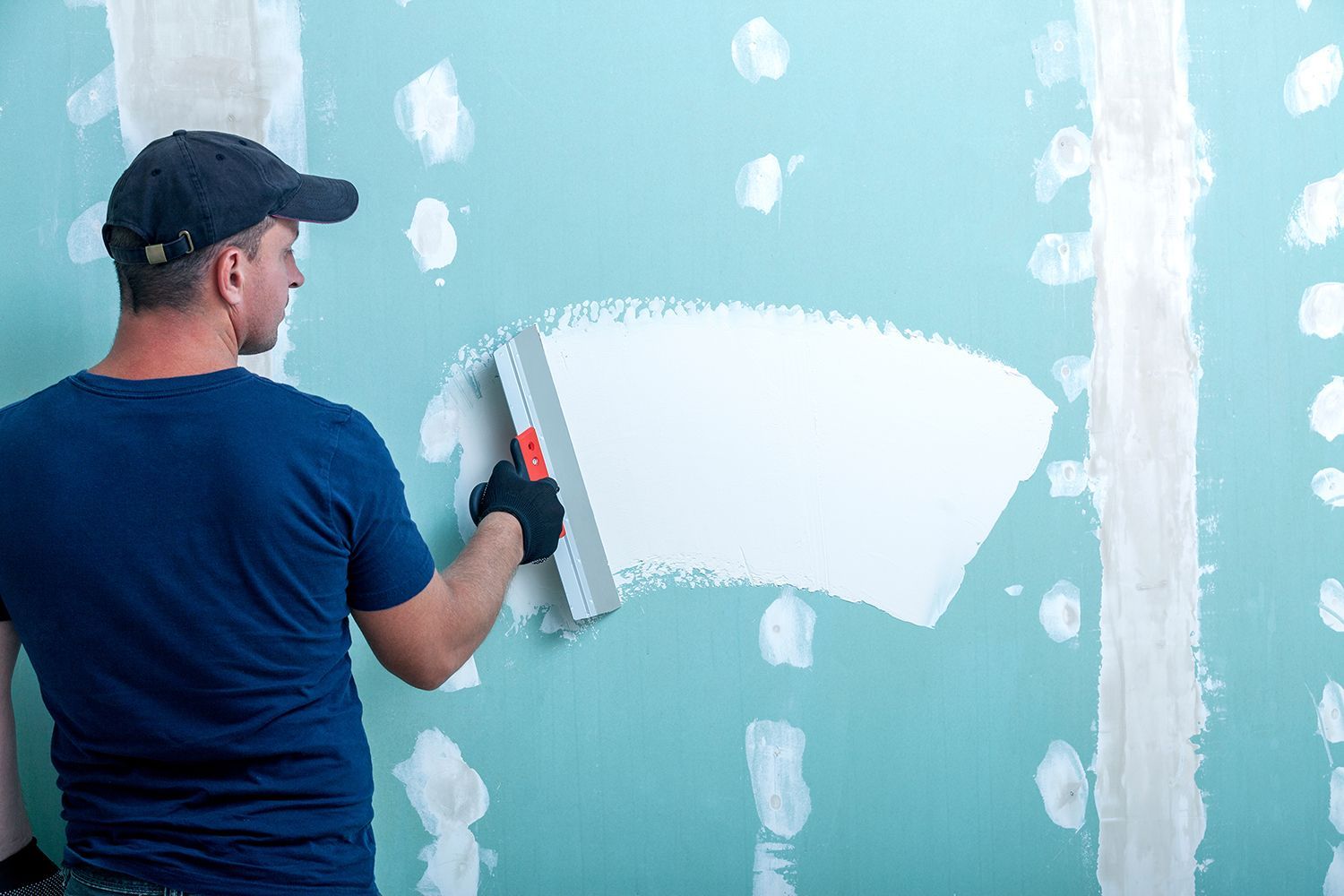 A contractor applying putty on a drywall. A contractor applying putty on a drywall.