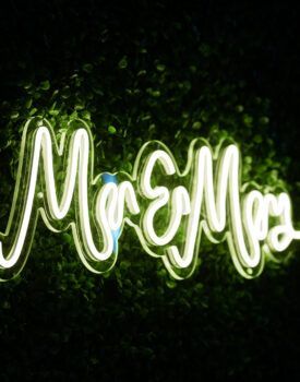 A neon sign that says `` mr. and mrs. '' is glowing in the dark.