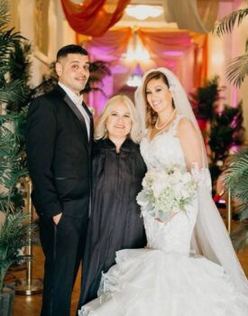 A bride and groom are posing for a picture with their wedding planner.