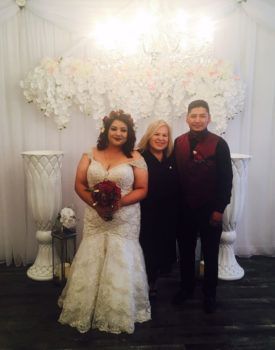 A bride and groom are posing for a picture with a wedding officiant.