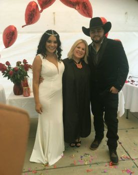 A bride and groom are posing for a picture with a judge and a man in a cowboy hat.