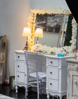 A vanity with a chair and a mirror in a room.