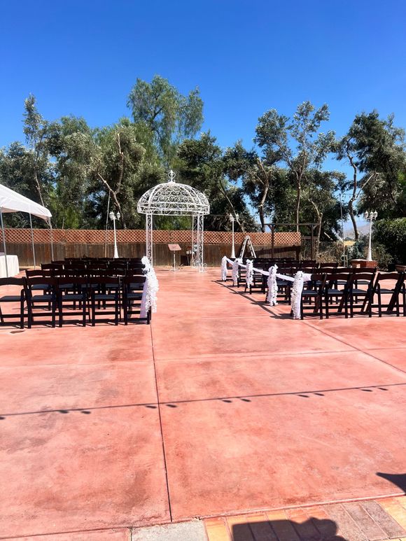 A row of chairs are lined up in front of a gazebo for a wedding ceremony.