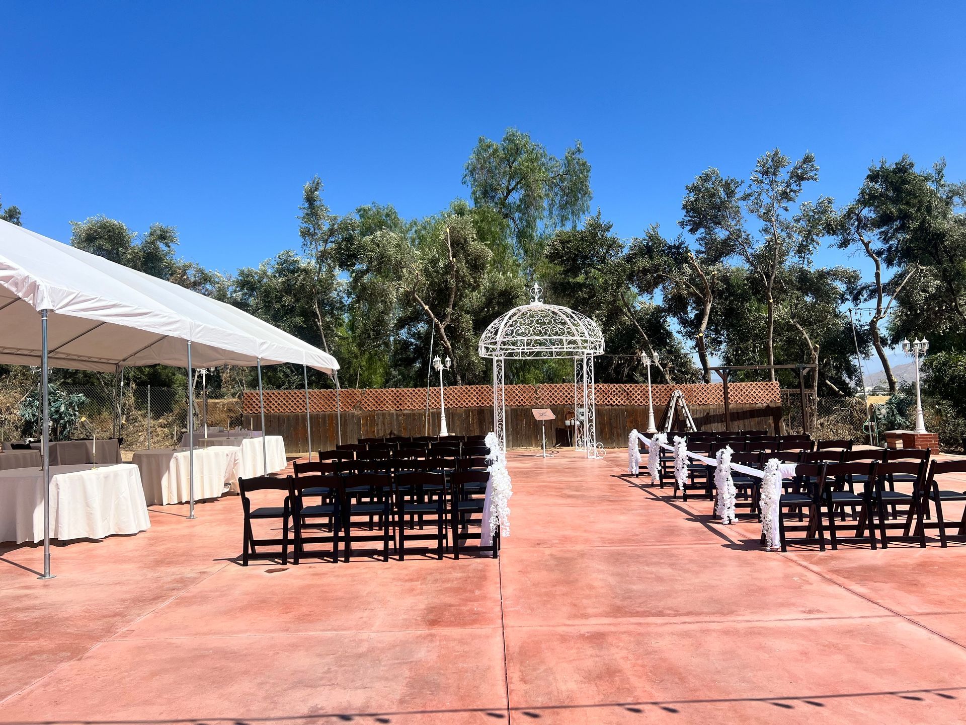 A row of chairs are lined up in front of a white tent for a wedding ceremony.