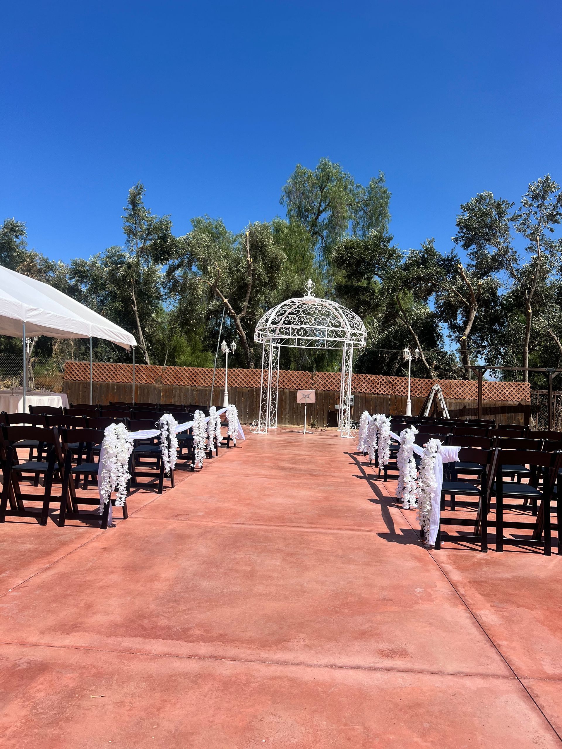 A row of chairs are lined up in front of a gazebo for a wedding ceremony.