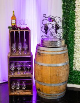 A wooden barrel sitting on top of a table next to a bottle of wine and wine glasses.