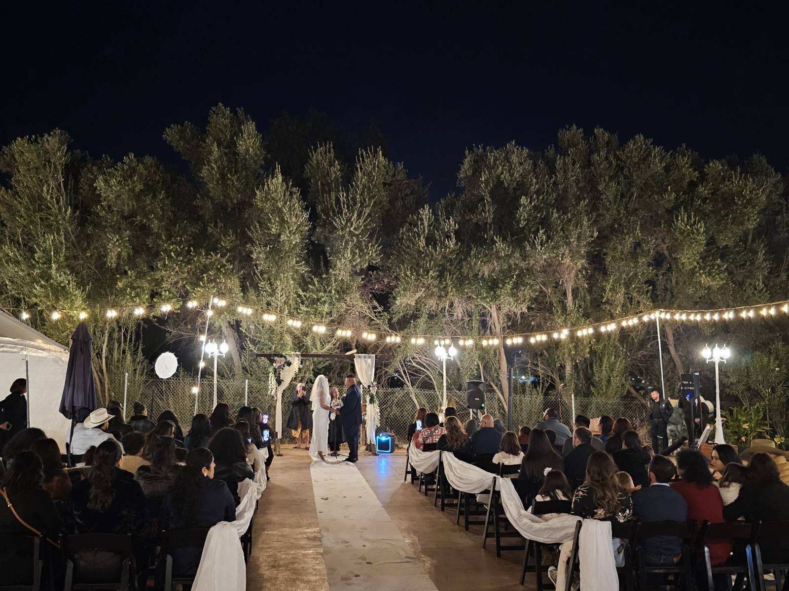 A wedding ceremony is taking place in the woods at night.