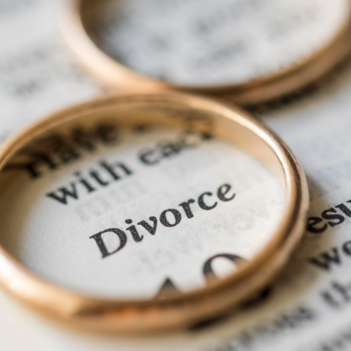 Two gold wedding rings rest on a page with the word