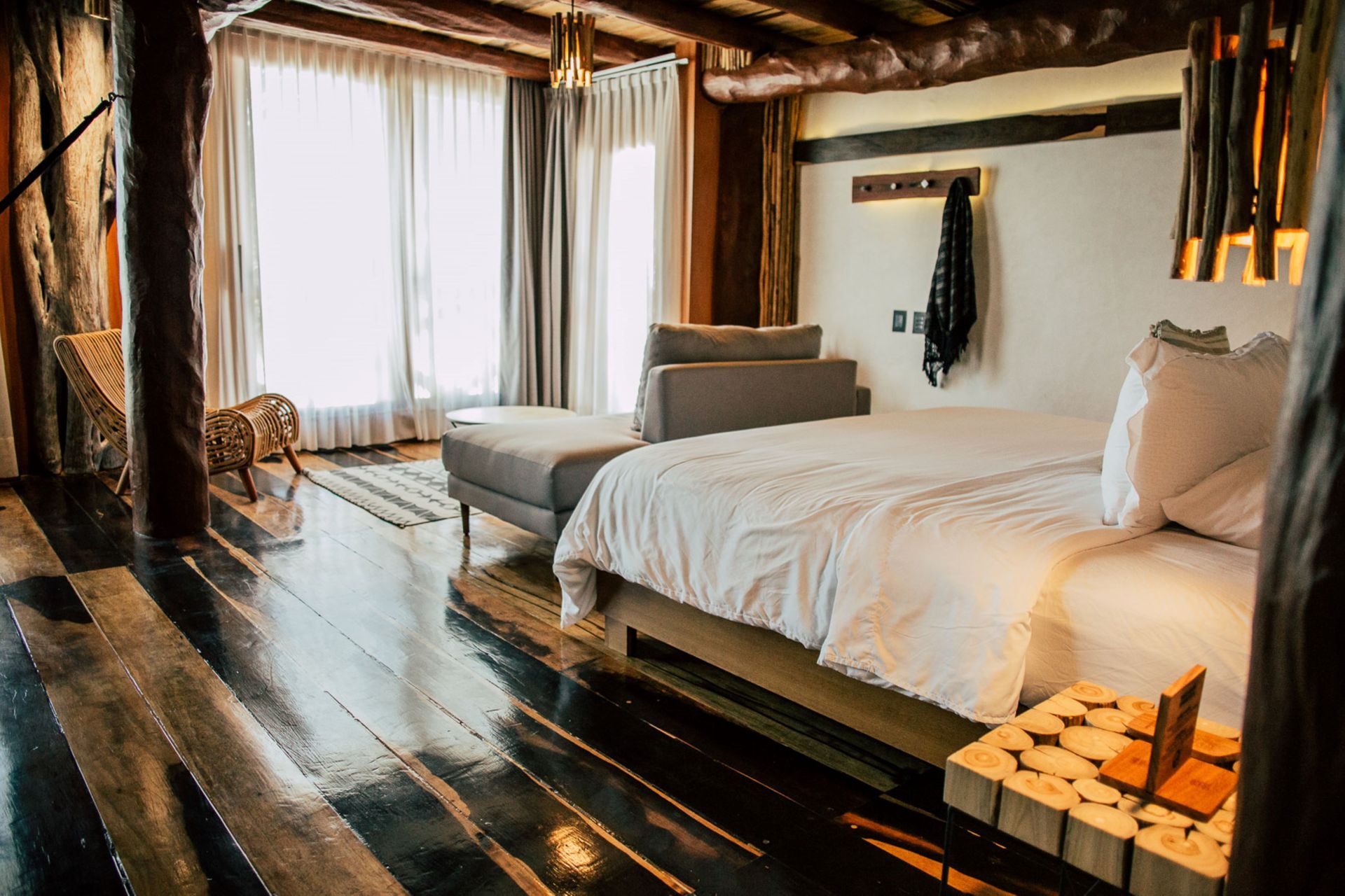 Cozy bedroom with wooden decor, bed, couch, and sheer curtains.