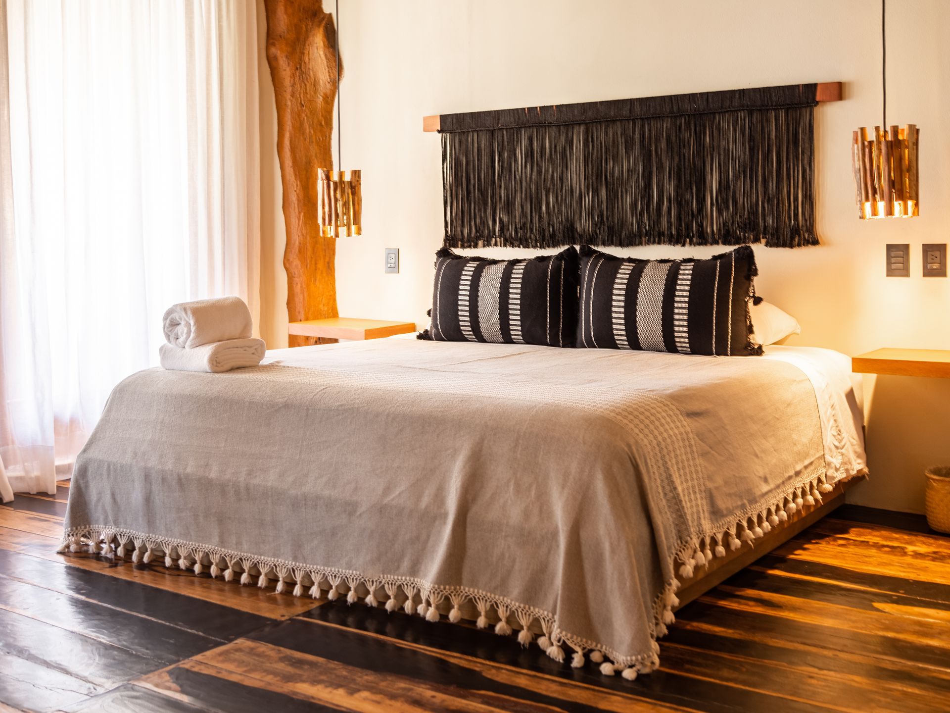 Bedroom with king bed, decorative pillows, woven headboard, and tassel blanket.