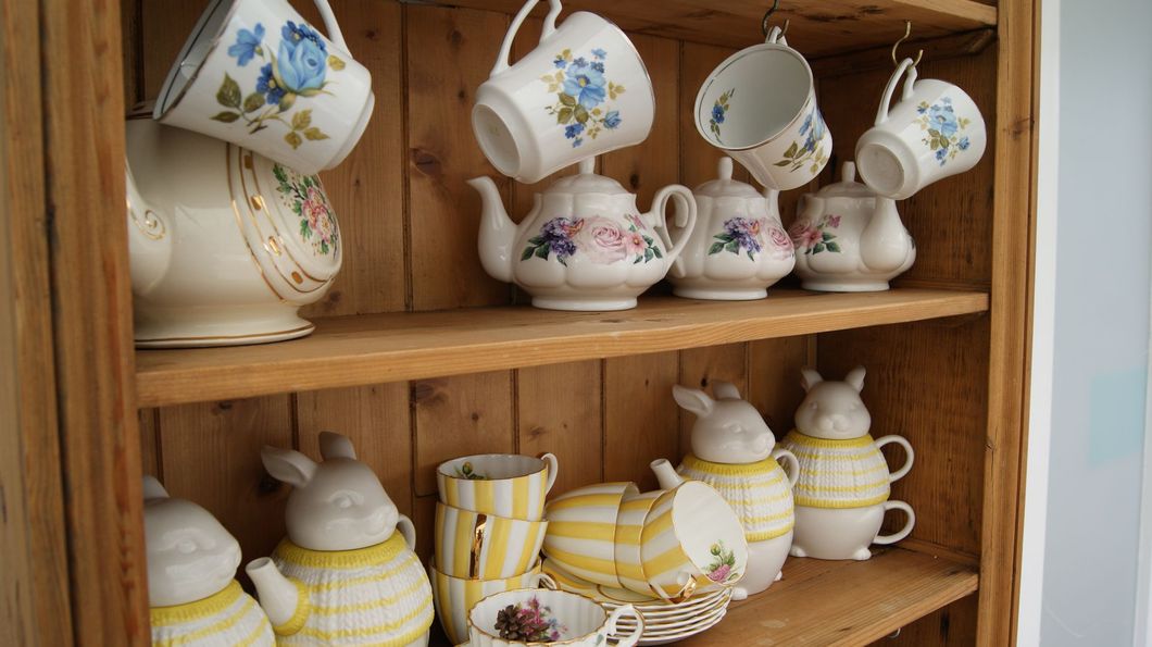 a wooden shelf with teapots and cups on it