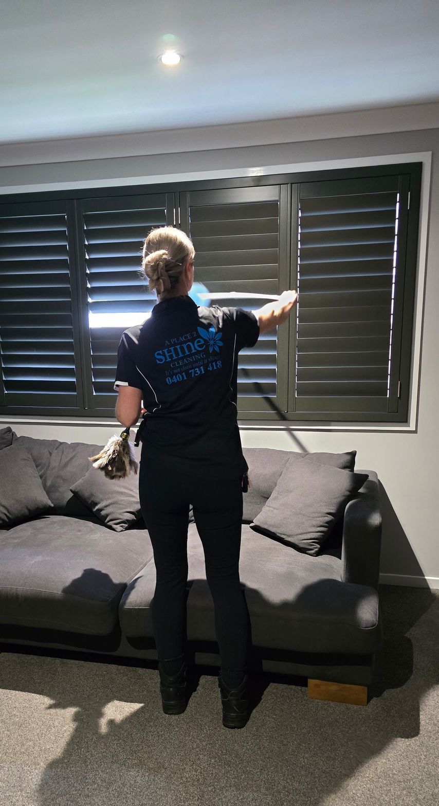 A Woman is Cleaning some blinds on a window — A Place 2 Shine In Chisholm, NSW