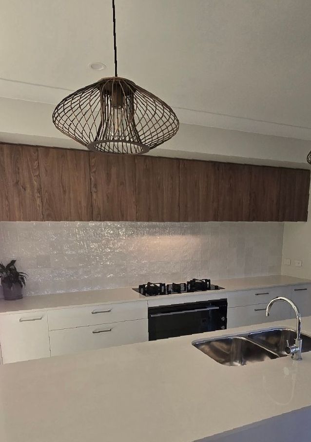 A Kitchen With White Cabinets and a Blue Glass Backsplash — A Place 2 Shine In Bolwarra, NSW