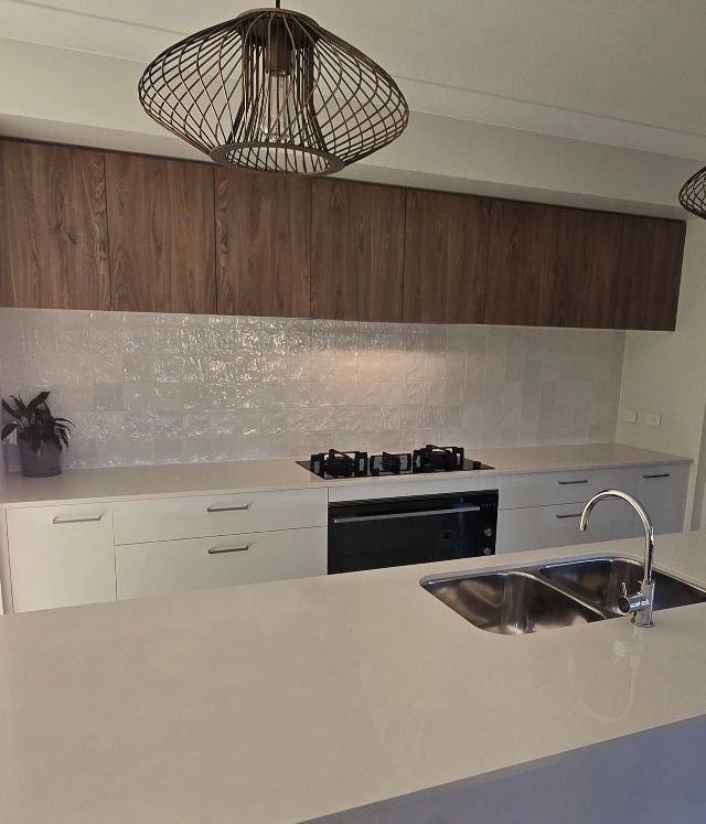 A clean kitchen area with white splashback — A Place 2 Shine In Louth Park, NSW