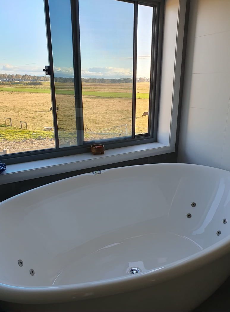 A Bathtub in a Bathroom Next to a Window With a View of a Field — A Place 2 Shine In Louth Park, NSW