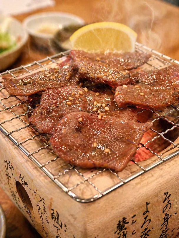 Creamy udon noodles topped with strips of nori and sesame seeds, served in a dark textured bowl on a rustic table.